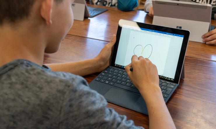 een man met behulp van een laptop computer zittend op de top van een tafel